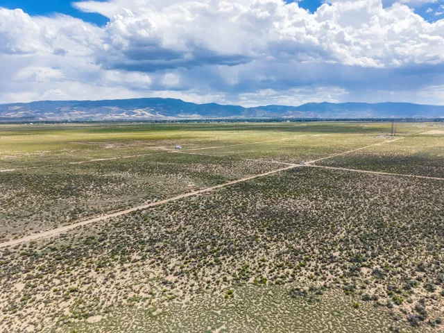 Expansive open land with natural desert vegetation, defined unpaved roads, and distant mountain backdrops