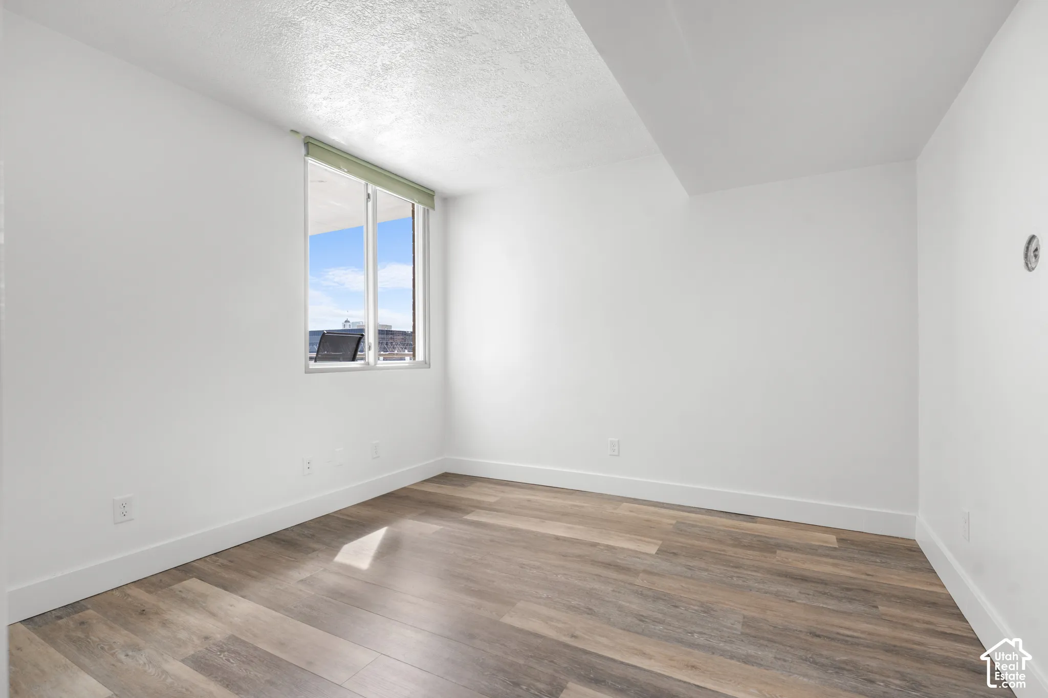 Neutral color palette, wood-finish flooring, large window, high ceilings, recessed window