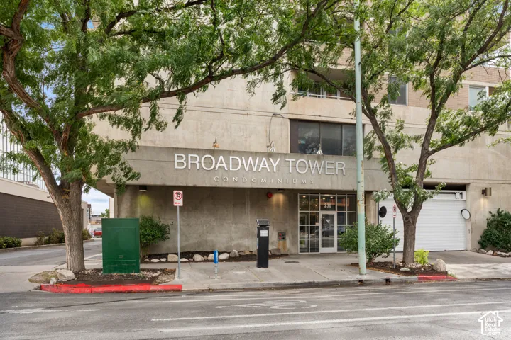 Concrete facade with "Broadway Tower Condominiums" signage, glass entry doors, and an integrated garage