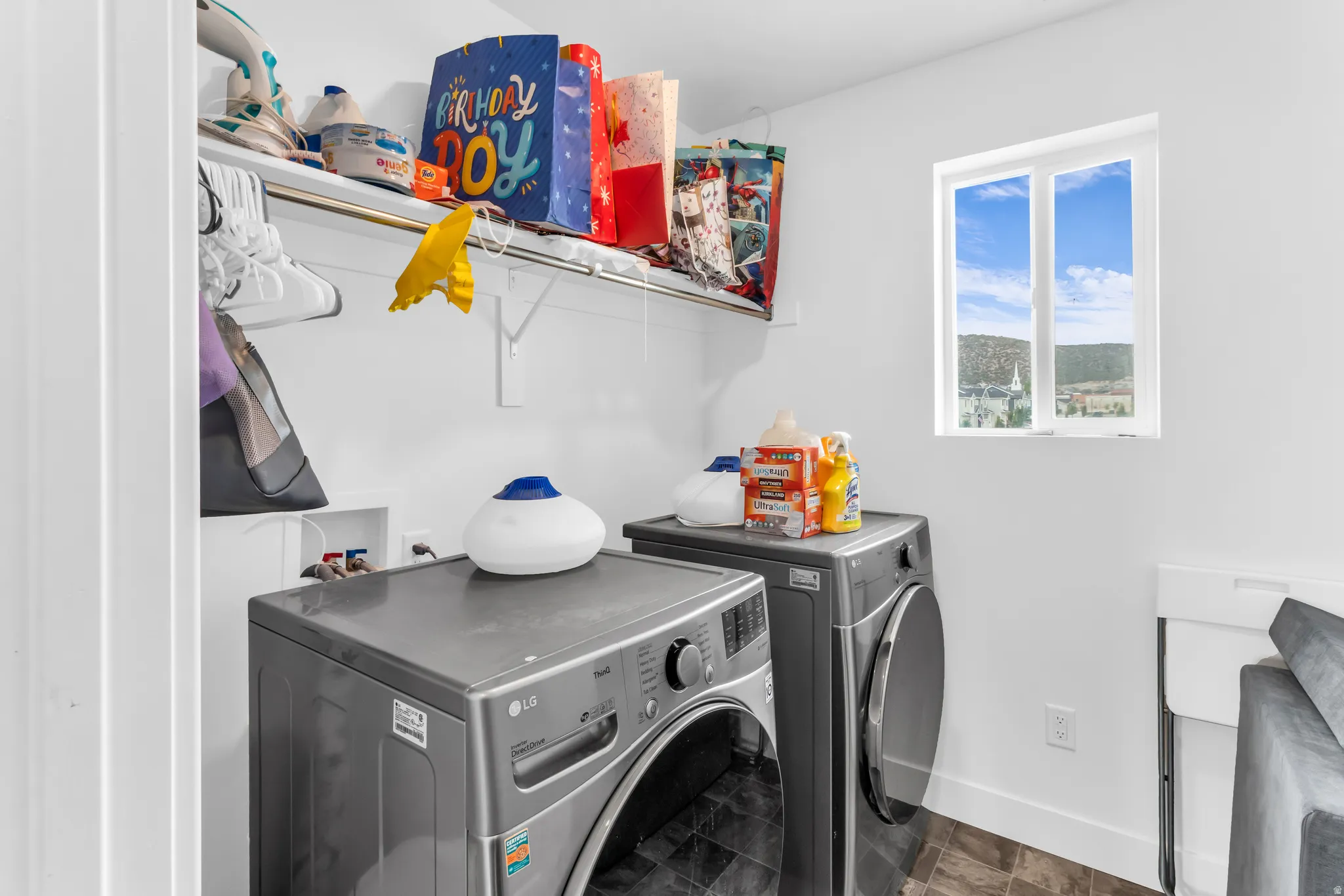 Dedicated laundry area featuring a window, built-in shelving, and a hanging rod