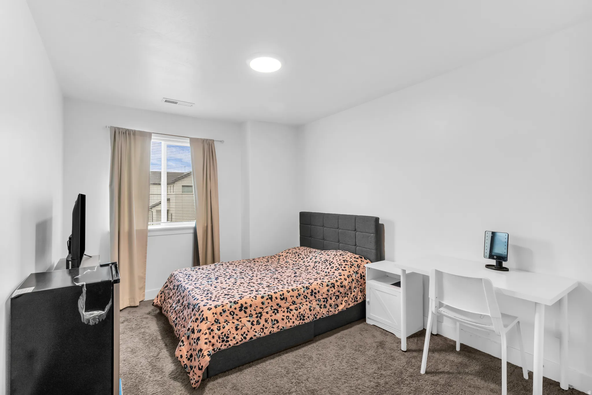 Recessed lighting illuminates this room featuring white walls and neutral-toned carpet