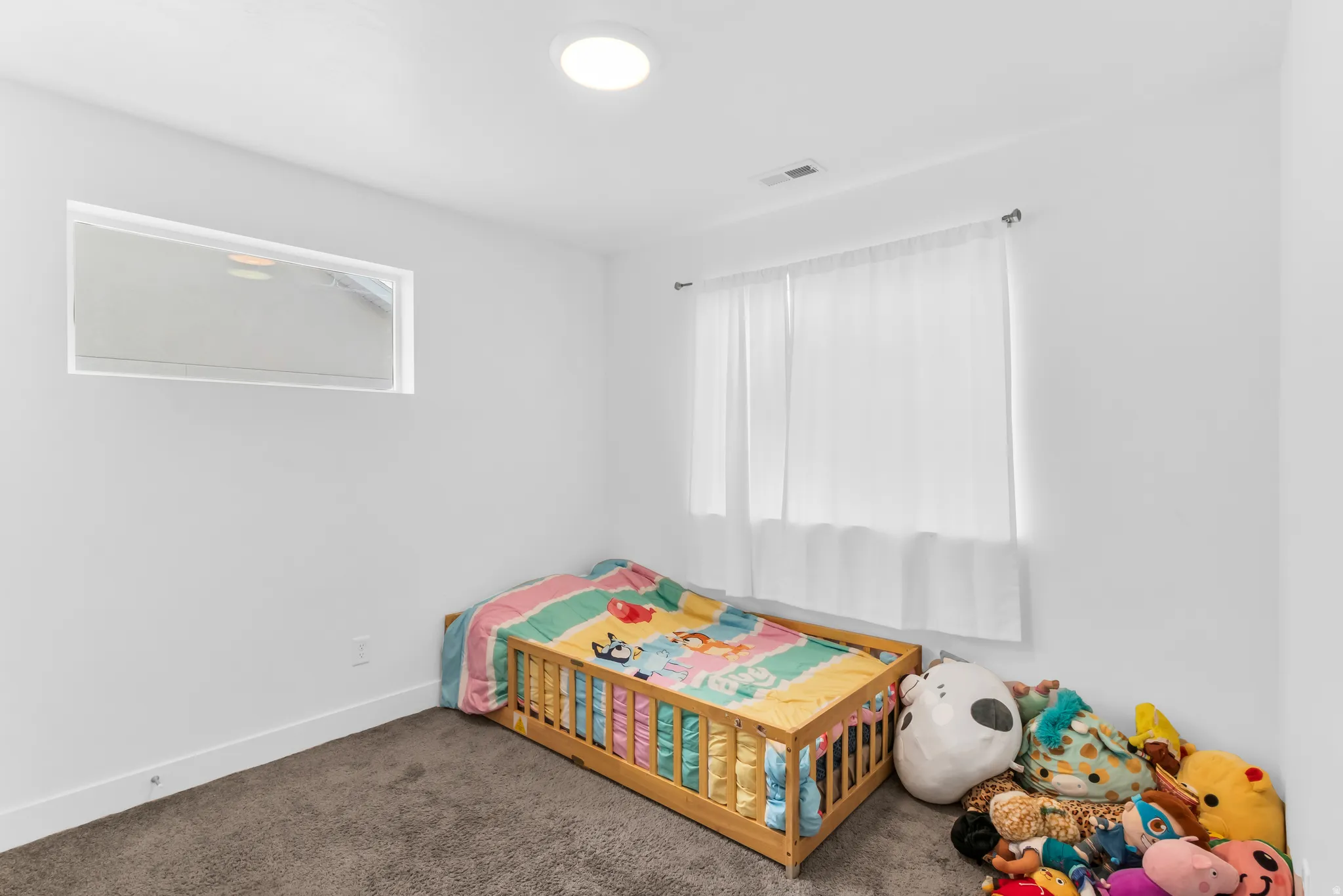 Recessed ceiling lighting, white walls, and a window with sheer curtains