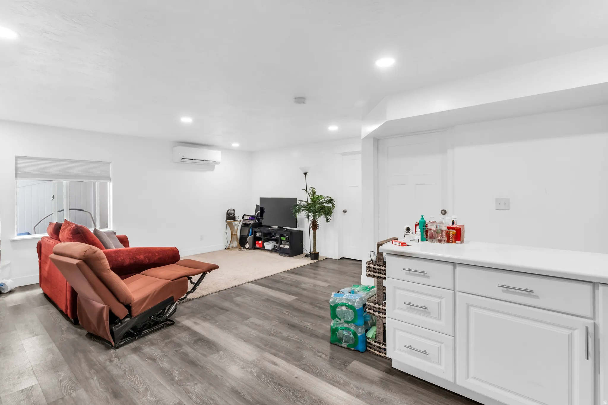 Spacious interior with wood-finish flooring, recessed lighting, and a built-in white cabinetry unit with a white countertop