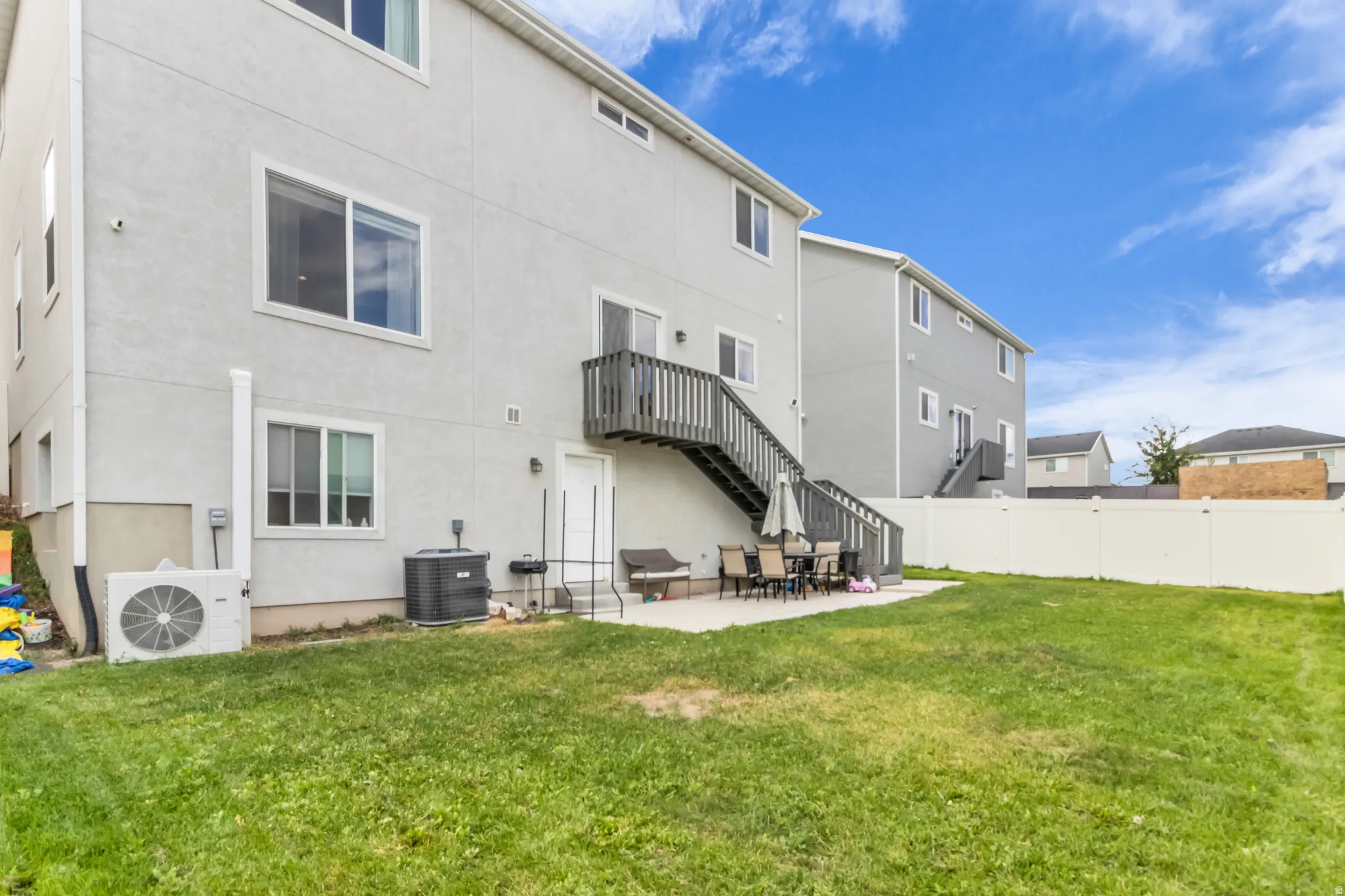 Expansive backyard featuring a patio area, a privacy fence, and a two-story exterior with a balcony