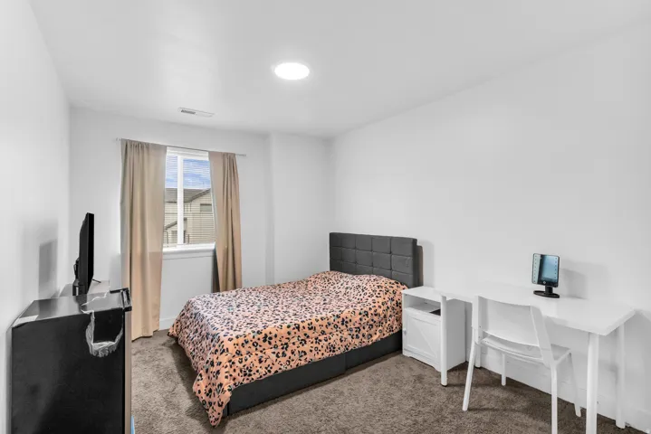 Recessed lighting illuminates this room featuring white walls and neutral-toned carpet