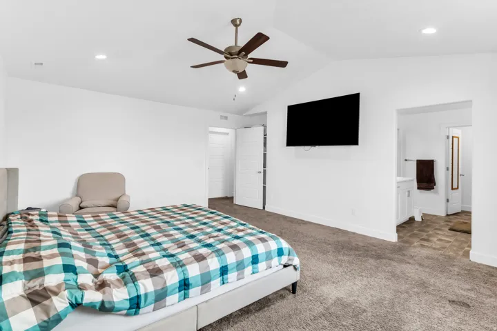 Carpeted bedroom with vaulted ceilings, recessed lighting, and a ceiling fan
