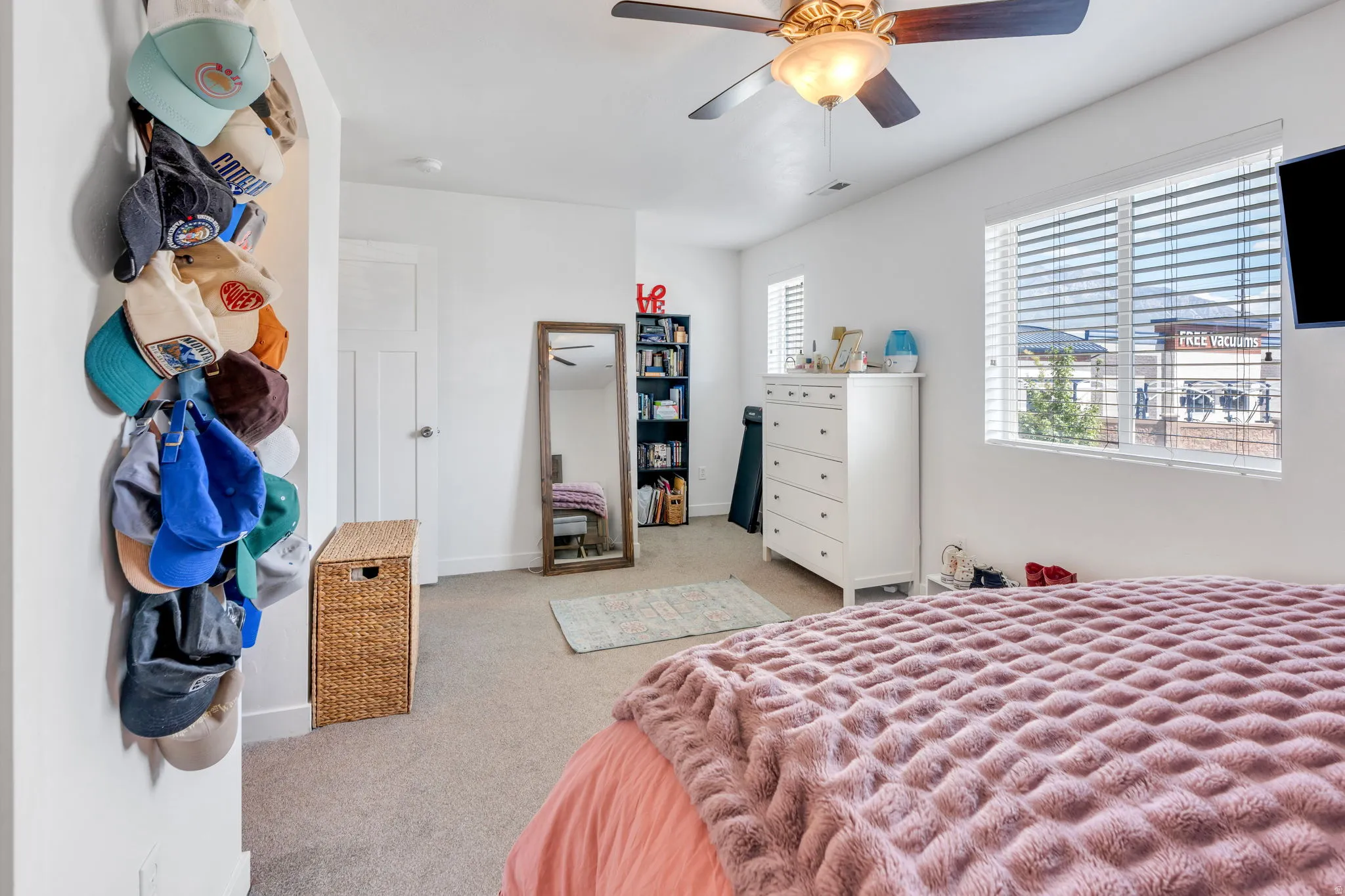 Carpeted room featuring a ceiling fan with integrated lighting and a window with horizontal blinds
