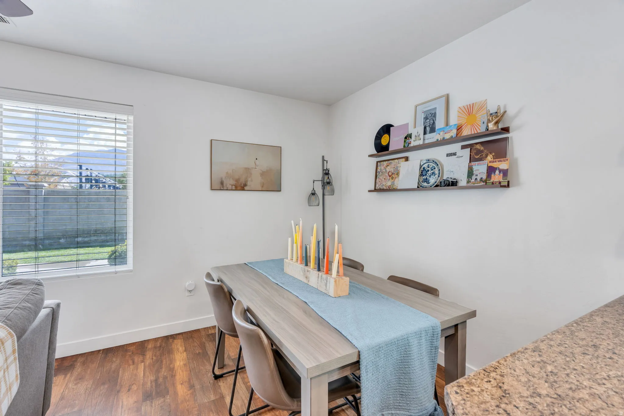 Wood-finish flooring, white walls, and a window with horizontal blinds