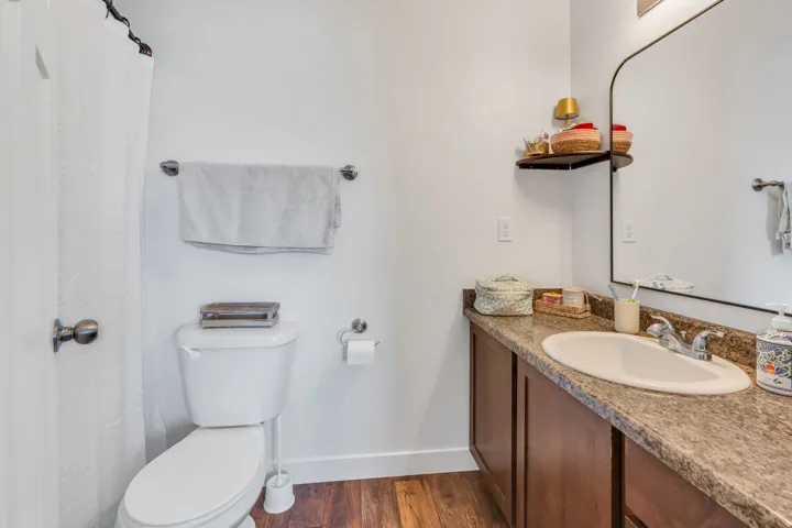 Wood-finish flooring, white walls, and a built-in vanity with a countertop and undermount sink