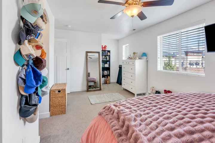 Carpeted room featuring a ceiling fan with integrated lighting and a window with horizontal blinds