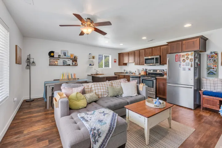 Open-concept living area featuring wood-finish flooring, a ceiling fan with integrated lighting, and recessed lighting