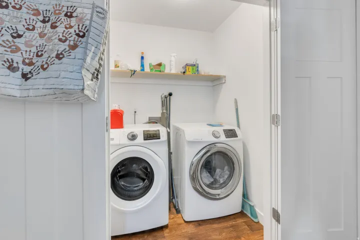 Dedicated laundry area with wood-finish flooring and an upper storage shelf