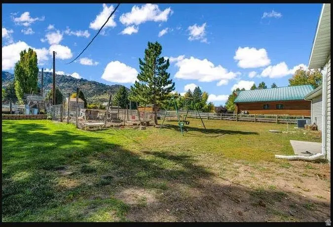 Expansive grassy yard with mature trees and a fenced perimeter