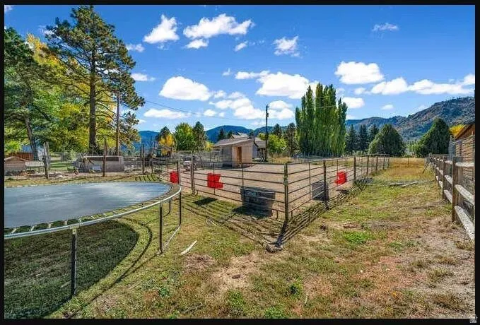 Fenced outdoor area featuring a metal corral and wooden fencing