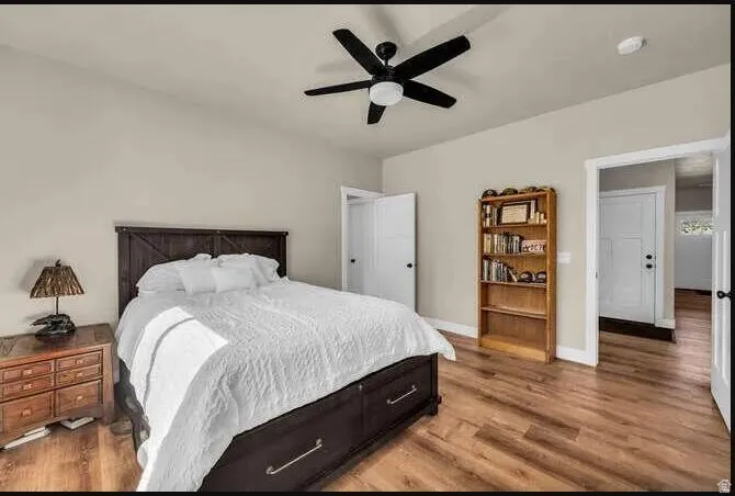 Wood-finish flooring, ceiling fan, and white interior doors
