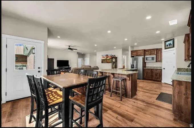 Wood-finish flooring, recessed lighting, wood cabinetry, stainless steel appliances, and a kitchen island with seating