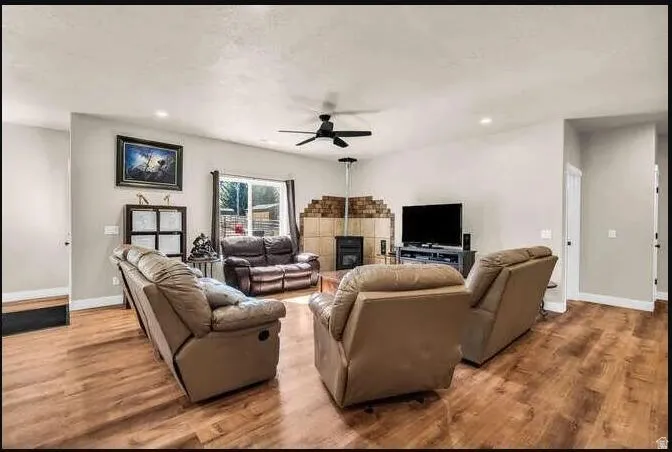 Wood-finish flooring, recessed lighting, ceiling fan, and a floor-to-ceiling brick-surround fireplace