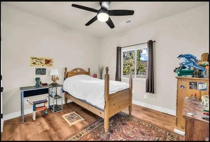 Wood-finish flooring, ceiling fan with integrated lighting, and a double-pane window