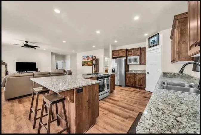 Kitchen featuring wood-finish flooring, granite countertops, stainless steel appliances, and wood cabinetry