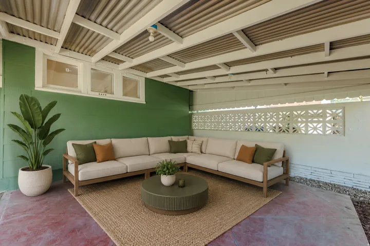 Covered patio featuring a corrugated metal ceiling, three transom windows, decorative concrete block wall, and concrete flooring