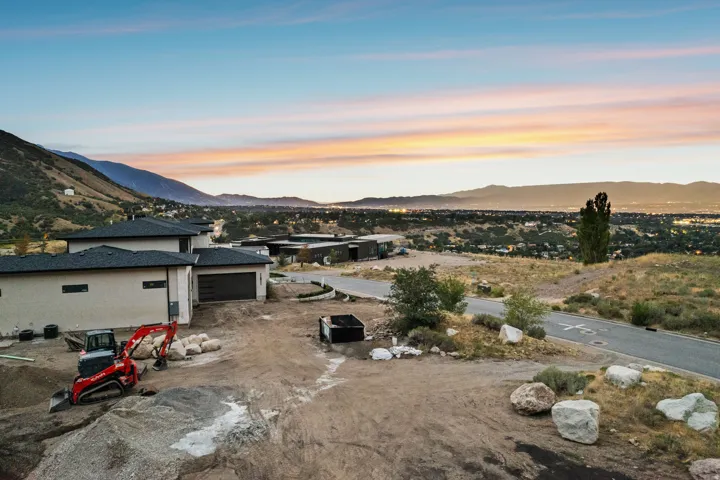 Paved road frontage with mountain backdrop and distant city lights