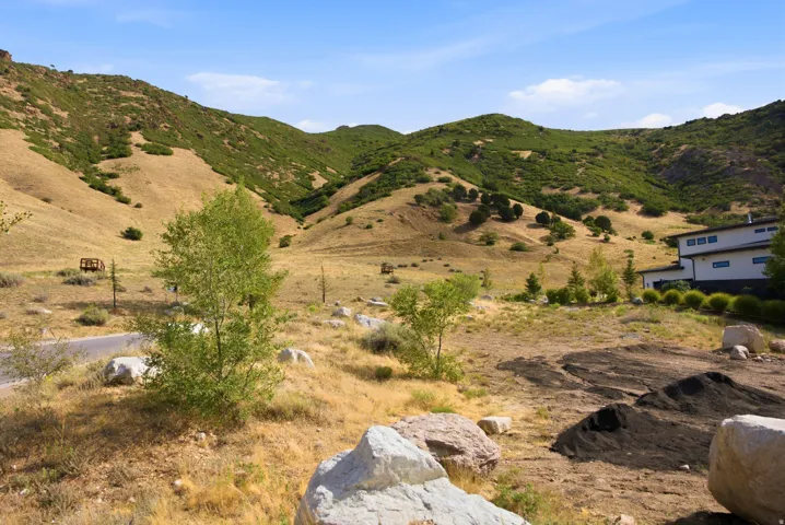 Property featuring natural hillside terrain, a partially developed building site, and a background of green mountain slopes