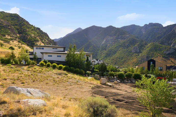 Expansive mountain landscape with a modern architectural home featuring a flat roof and multiple windows