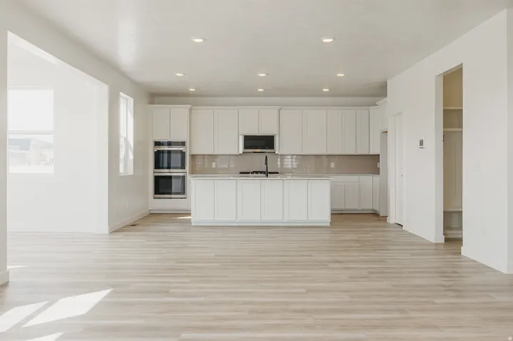 Open-concept living space featuring wood-finish flooring, recessed lighting, and a kitchen with white cabinetry