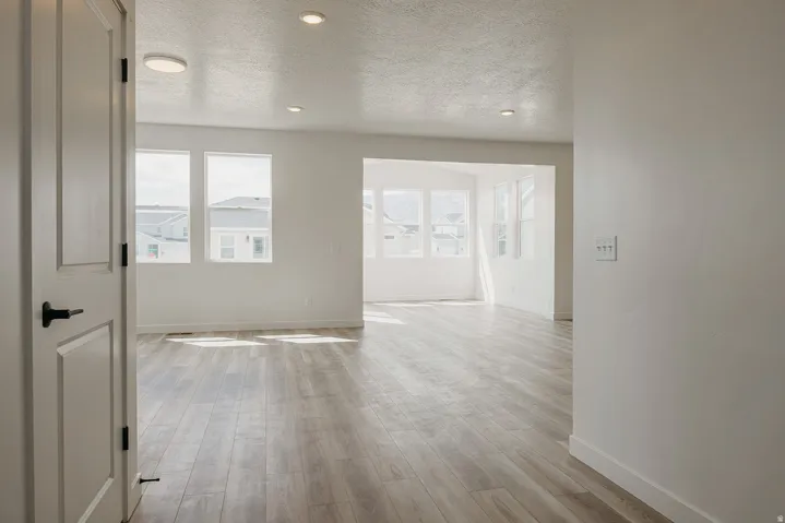 Expansive interior with light wood-finish flooring, recessed lighting, and multiple windows