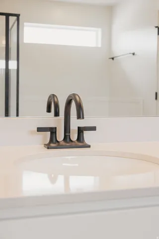 White countertop with an integrated sink, matte black faucet, and a large wall-mounted mirror
