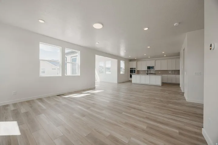 Expansive open-concept living area featuring wood-finish flooring, recessed lighting, and large windows
