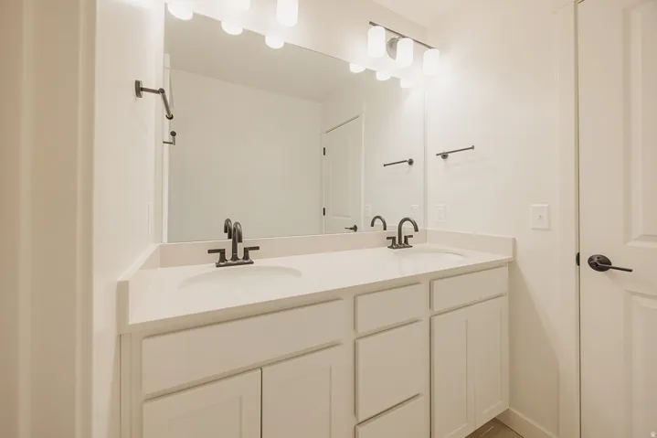 Dual vanity with white cabinetry and integrated sinks, matte black hardware, and a large wall-mounted mirror