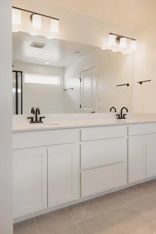 Dual vanity with white cabinetry and integrated sinks, matte black faucets, and overhead lighting fixtures