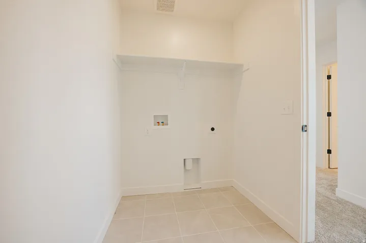 Utility area featuring tile flooring, a built-in shelf, and appliance hookups