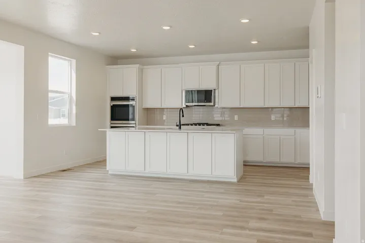 Kitchen featuring white cabinetry, a central island, stainless steel appliances, tile backsplash, and wood-finish flooring