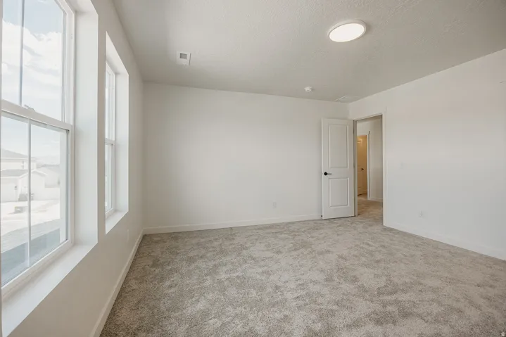 Neutral wall tones, gray carpet, multiple windows, recessed ceiling light, and interior door with dark hardware