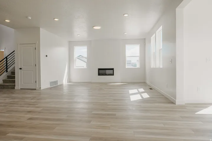 Spacious open-concept living area featuring wood-finish flooring, recessed lighting, and multiple windows