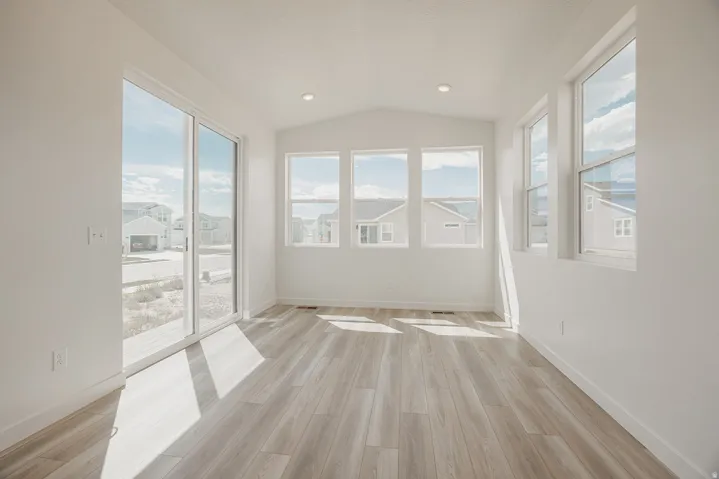 Wood-finish flooring, white walls, recessed lighting, expansive sliding glass door, and multiple windows