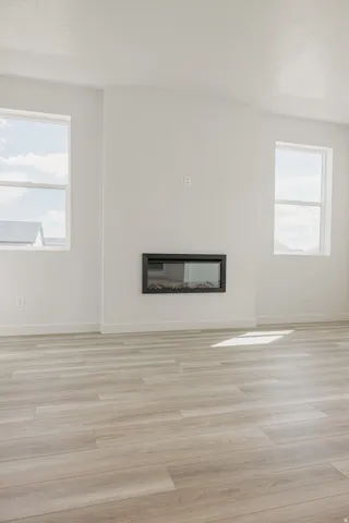 Wood-finish flooring, white walls, and an inset linear fireplace