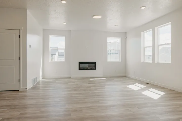 Recessed lighting throughout, wood-finish flooring, multiple windows, and a built-in electric fireplace