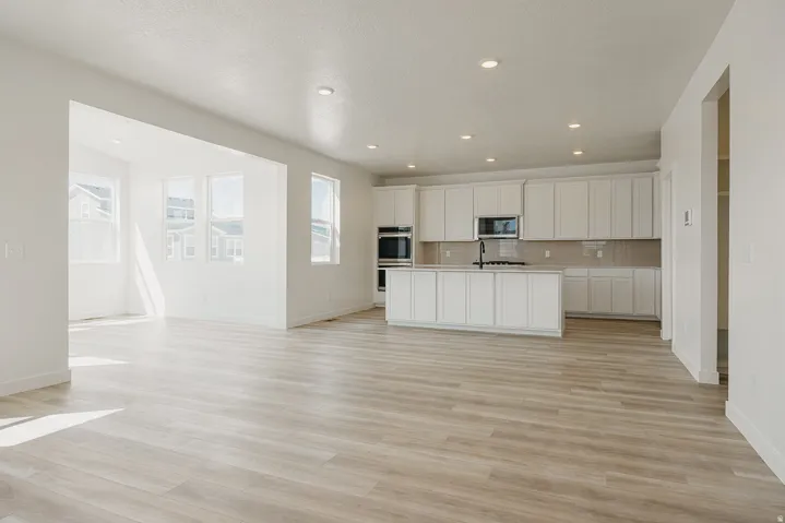 Expansive open-concept living area with light wood-finish flooring, recessed lighting, and a modern kitchen
