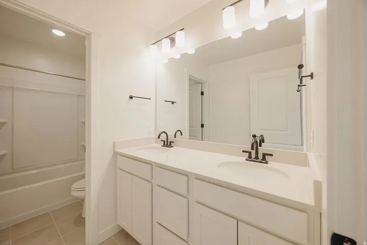 Dual vanity with integrated sinks, light-toned countertop, and dark-finished fixtures