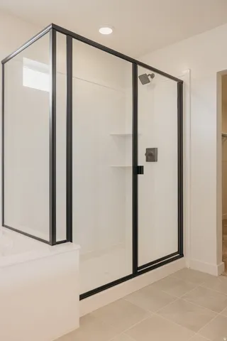 Glass-enclosed shower with matte black framing, built-in shelving, and a recessed ceiling light