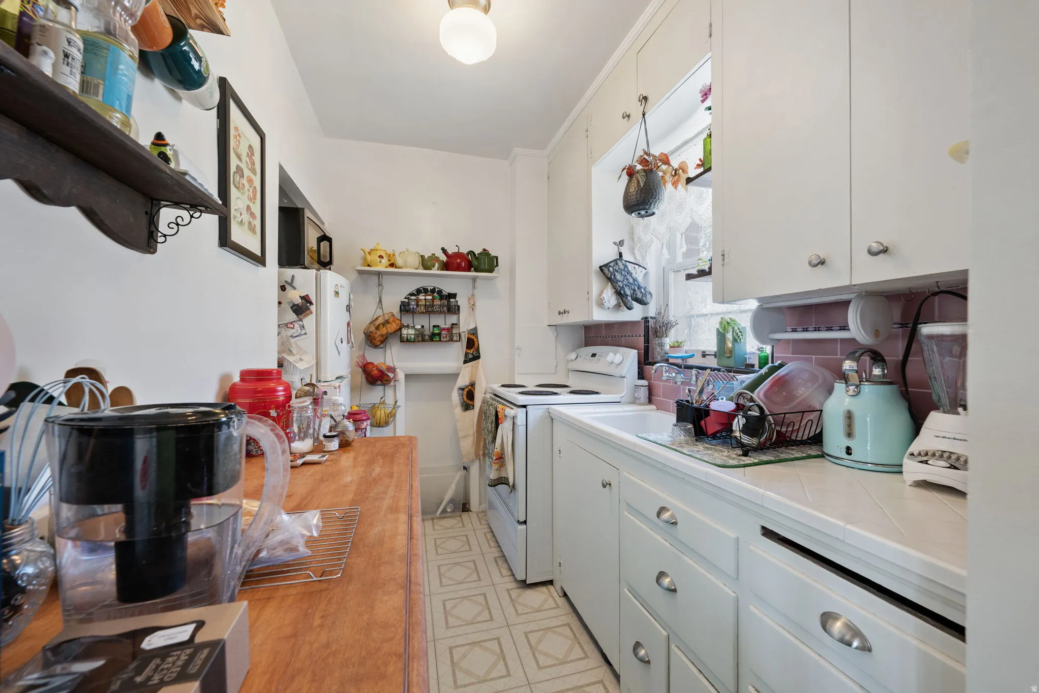 White cabinetry with curved drawer pulls, tile flooring, and a window with natural light