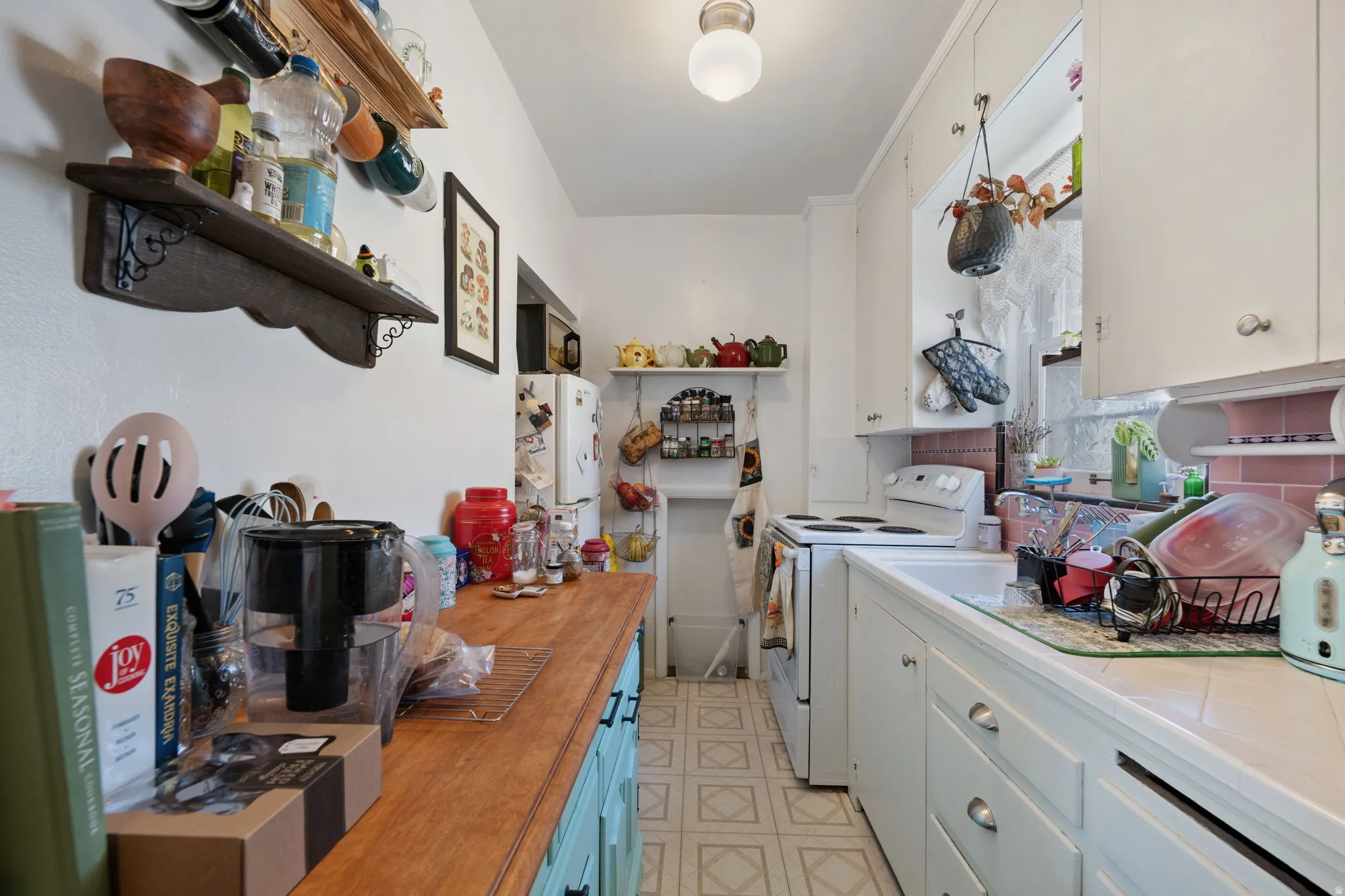 White cabinetry and appliances, wood-finish countertop, tile backsplash, and patterned flooring