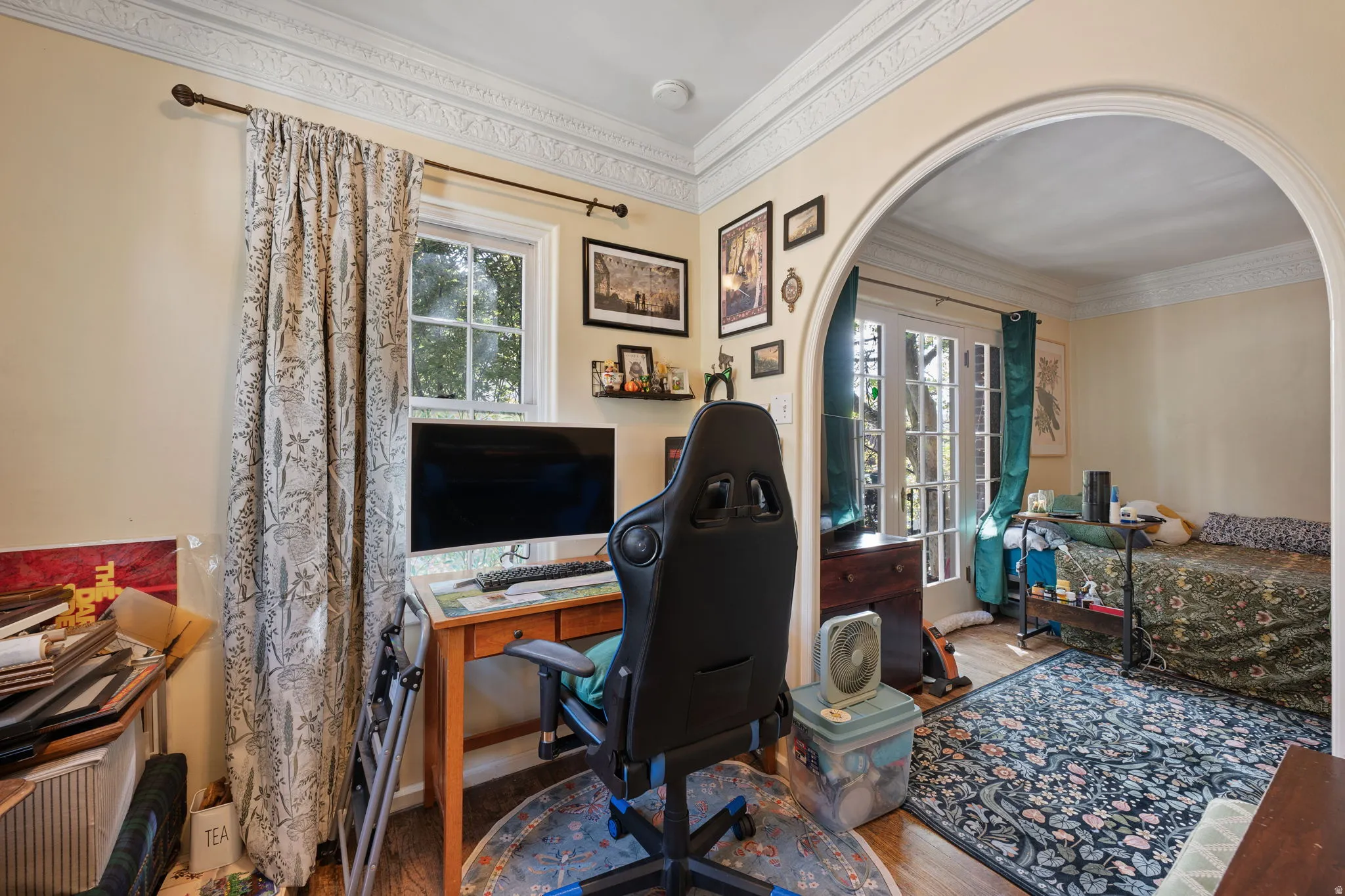 Decorative crown molding, arched doorway, wood-finish flooring, single window, double French doors