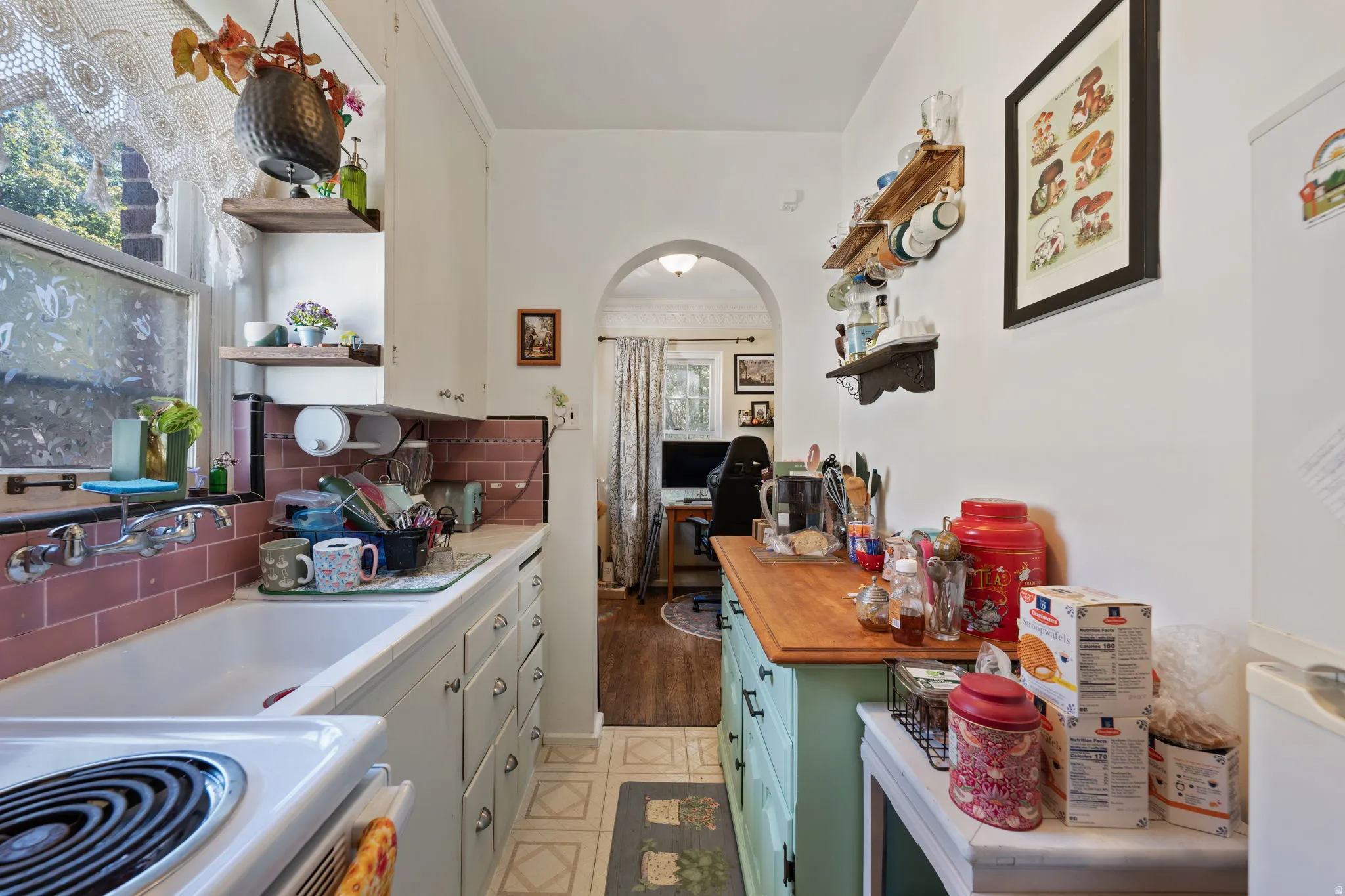 Compact kitchen with white cabinetry, a built-in white sink, and pink tiled backsplash