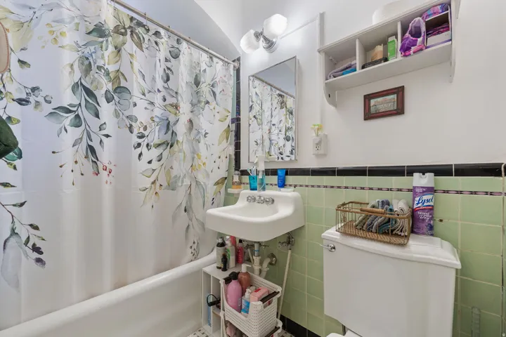 White ceramic bathtub, wall-mounted sink, toilet, and light fixture