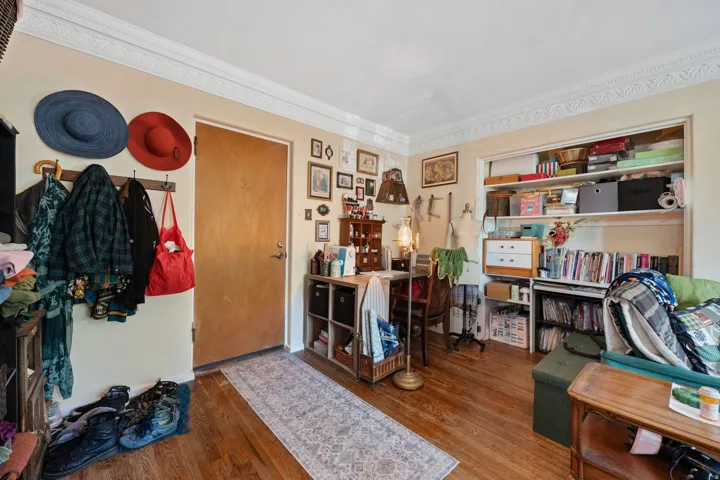 Hardwood flooring, decorative crown molding, and a built-in shelving unit
