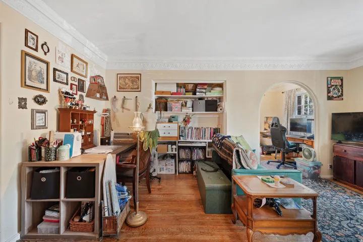 Hardwood flooring, decorative crown molding, cased archway, built-in shelving, and light wall finishes